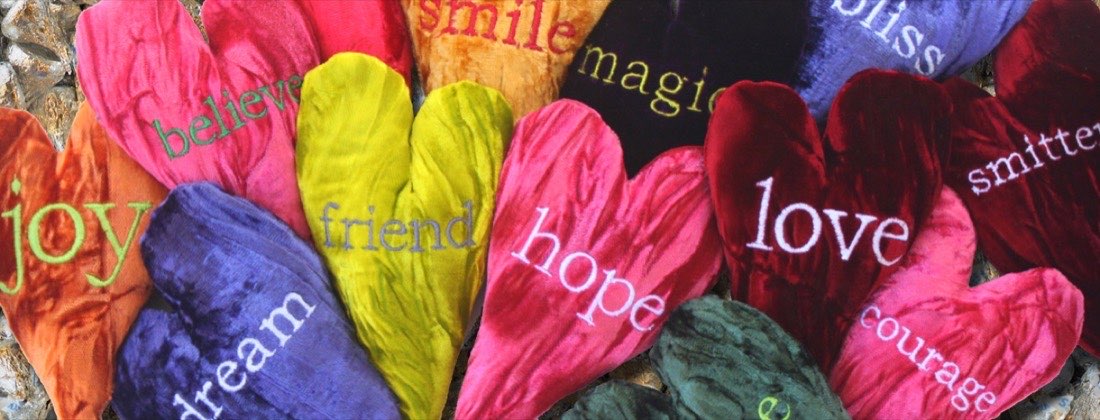 Crushed velvet heart pillows embroidered with the words joy, believe, friend, hope, love, courage and smitten